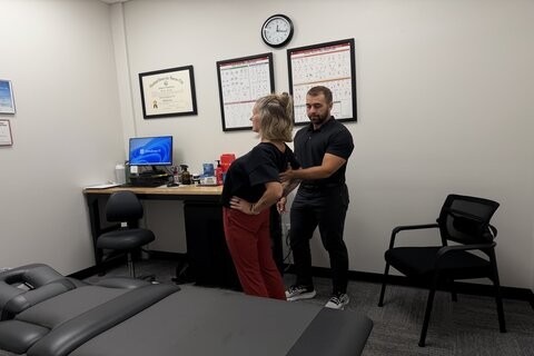 Chiropractor evaluating a patient's spine movement during a McKenzie Method assessment