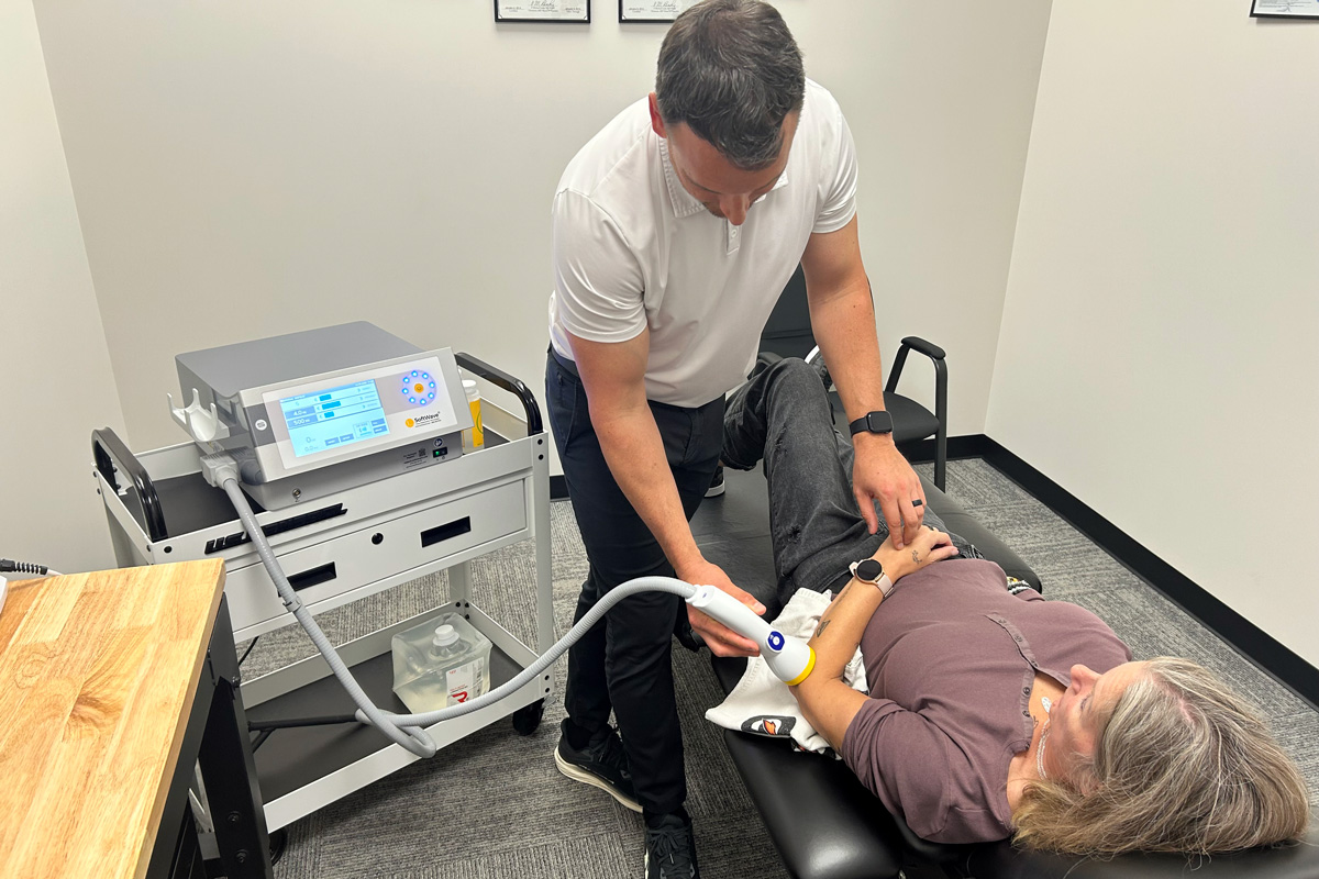 administering softwave therapy on patient's elbow
