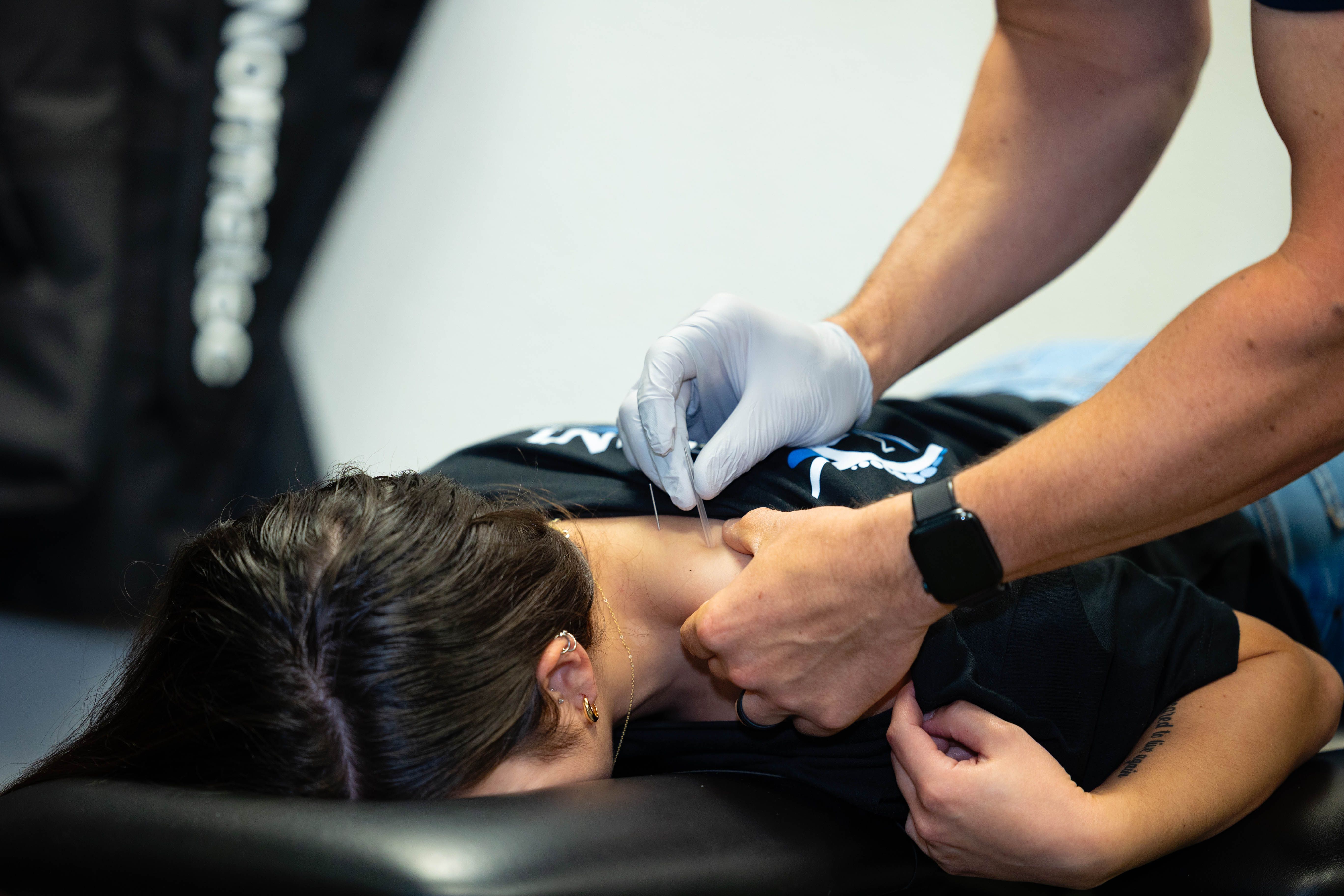 chiropractor dry needling a patient's shoulder for neck pain