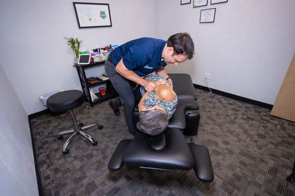 chiropractor performing a chiropractic adjustment to a patient's back